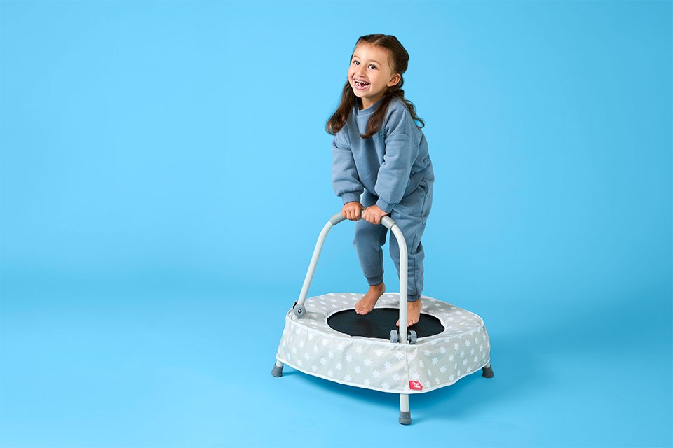 A girl standing on a Chad Valley indoor trampoline.